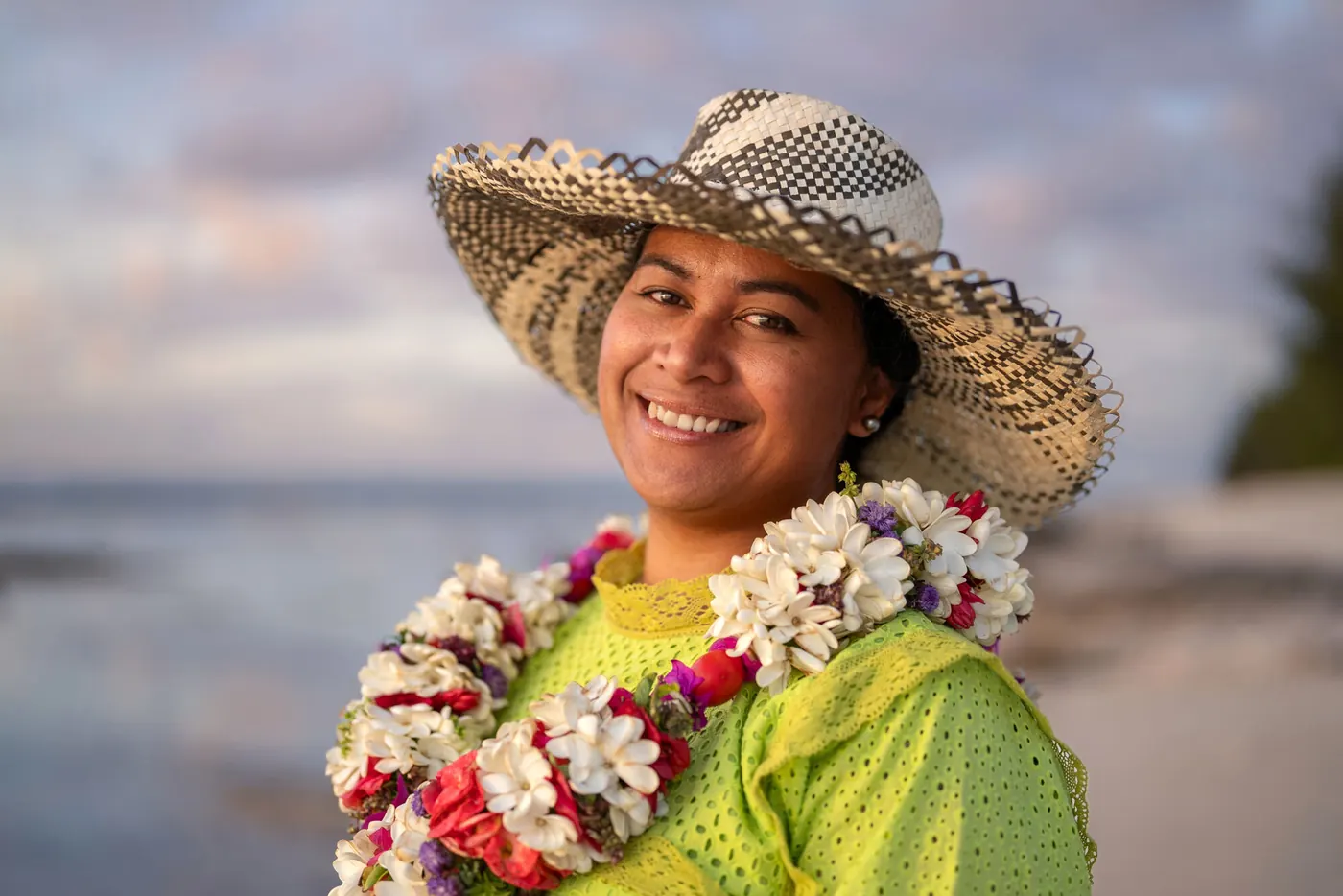 Donna polinesiana sorridente con collana di fiori e cappello intrecciato